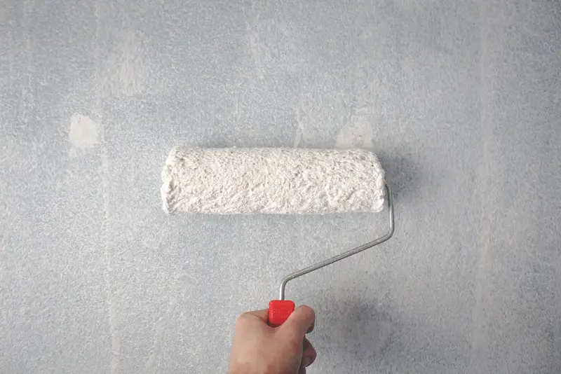 Hand rolt een muur strak wit met een verfroller